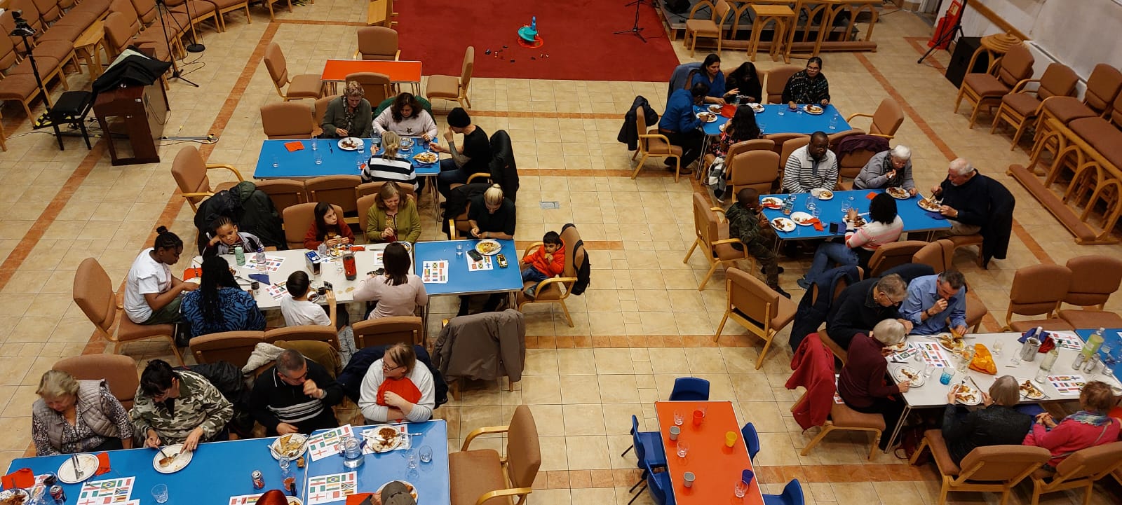 Aerial shot of people sat at groups of tables in a large room eating and in conversation
