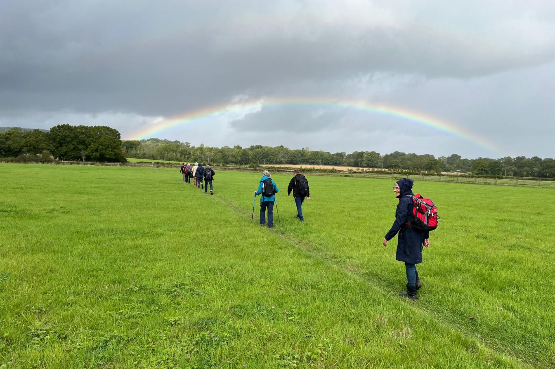 The pilgrims from Viborg and Guildford Dioceses walking across a field with a rainbow in the distance