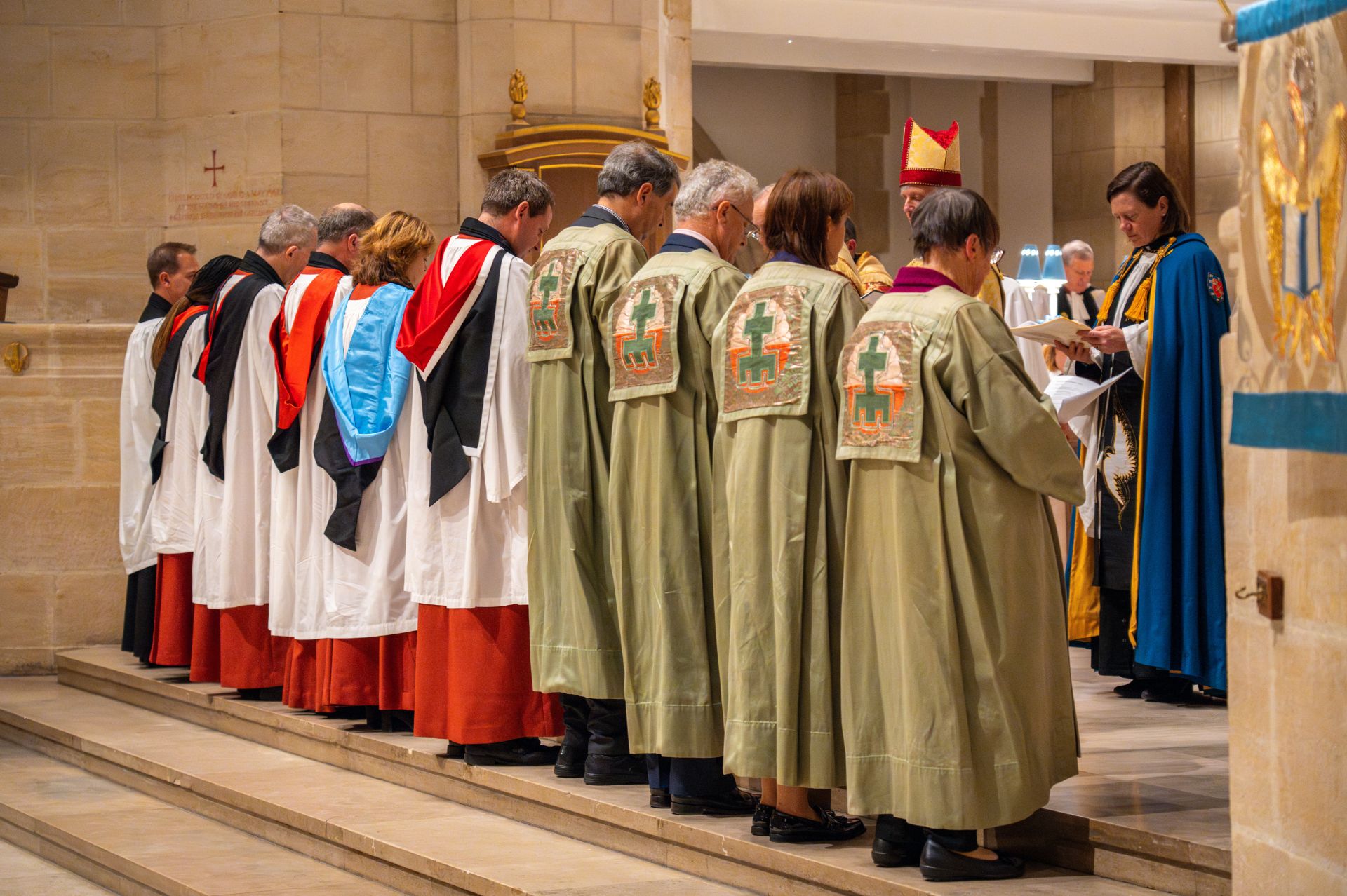 The Honorary Canon-designates stand side by side on the Quire steps in Guildford Cathedral waiting to be installed