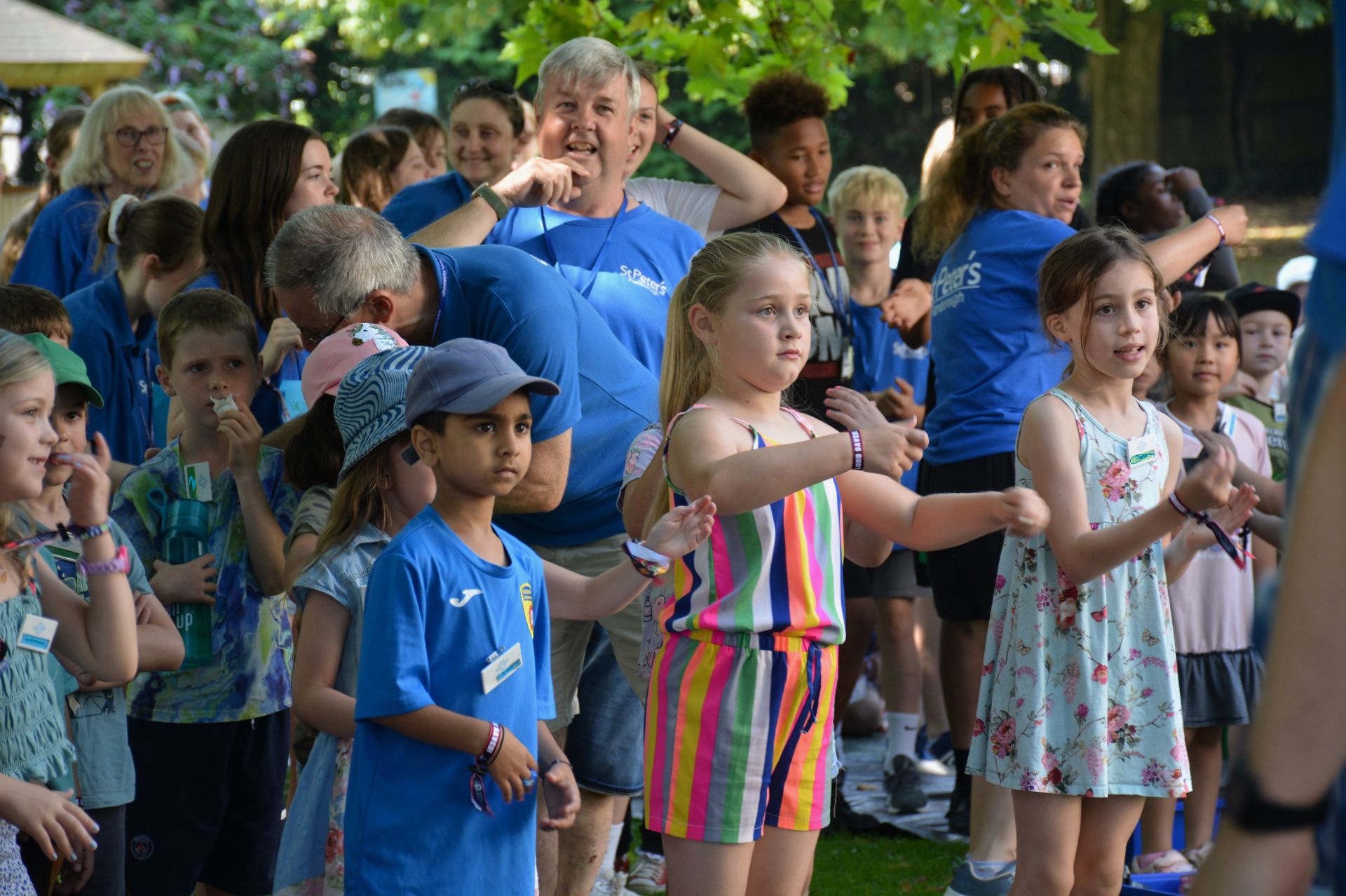 A group of children and adults joining in with actions for a song outside