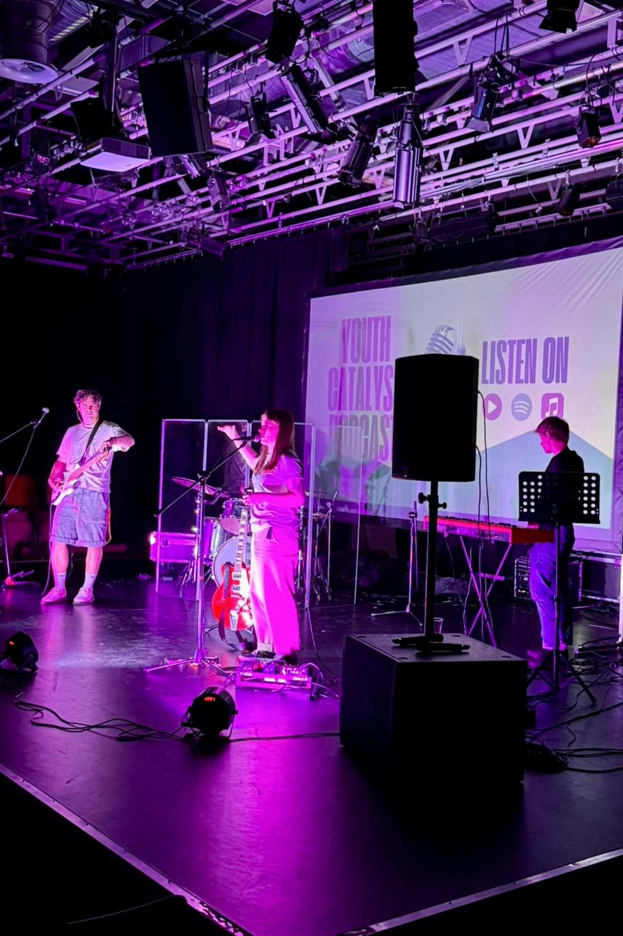 Image of a worship band on stage with singer, keyboard player and bass player