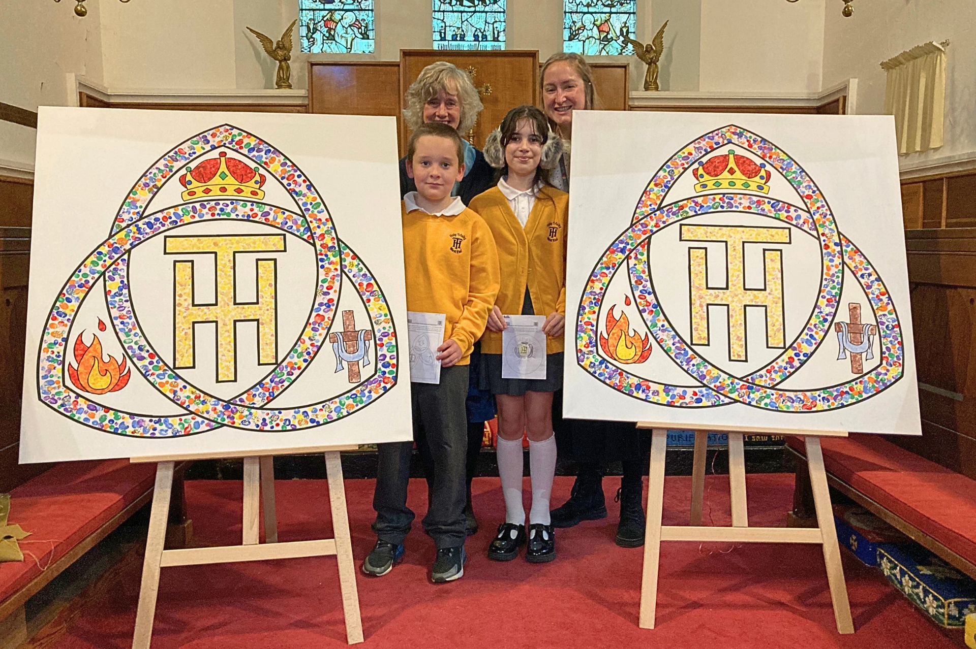 Artwork unveiled at the church with Revd Fiona, a teacher and the two pupils who desinged the artwork standing next to the canvases