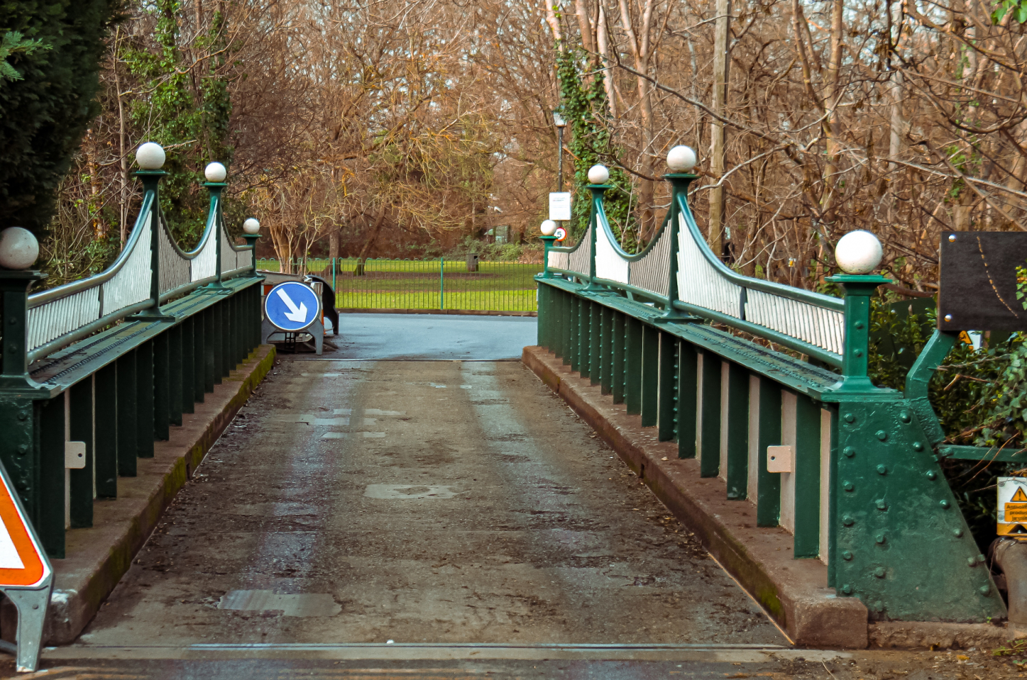 Ornate metal bridge with a blue arrow road sign, leading to other roads ahead