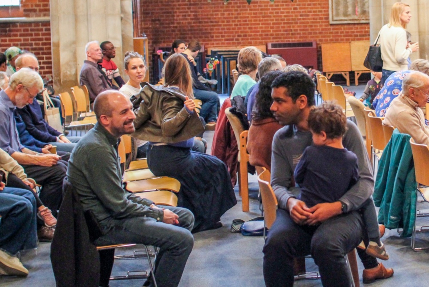 People of all ages sitting together to ahead of a church service in conversation