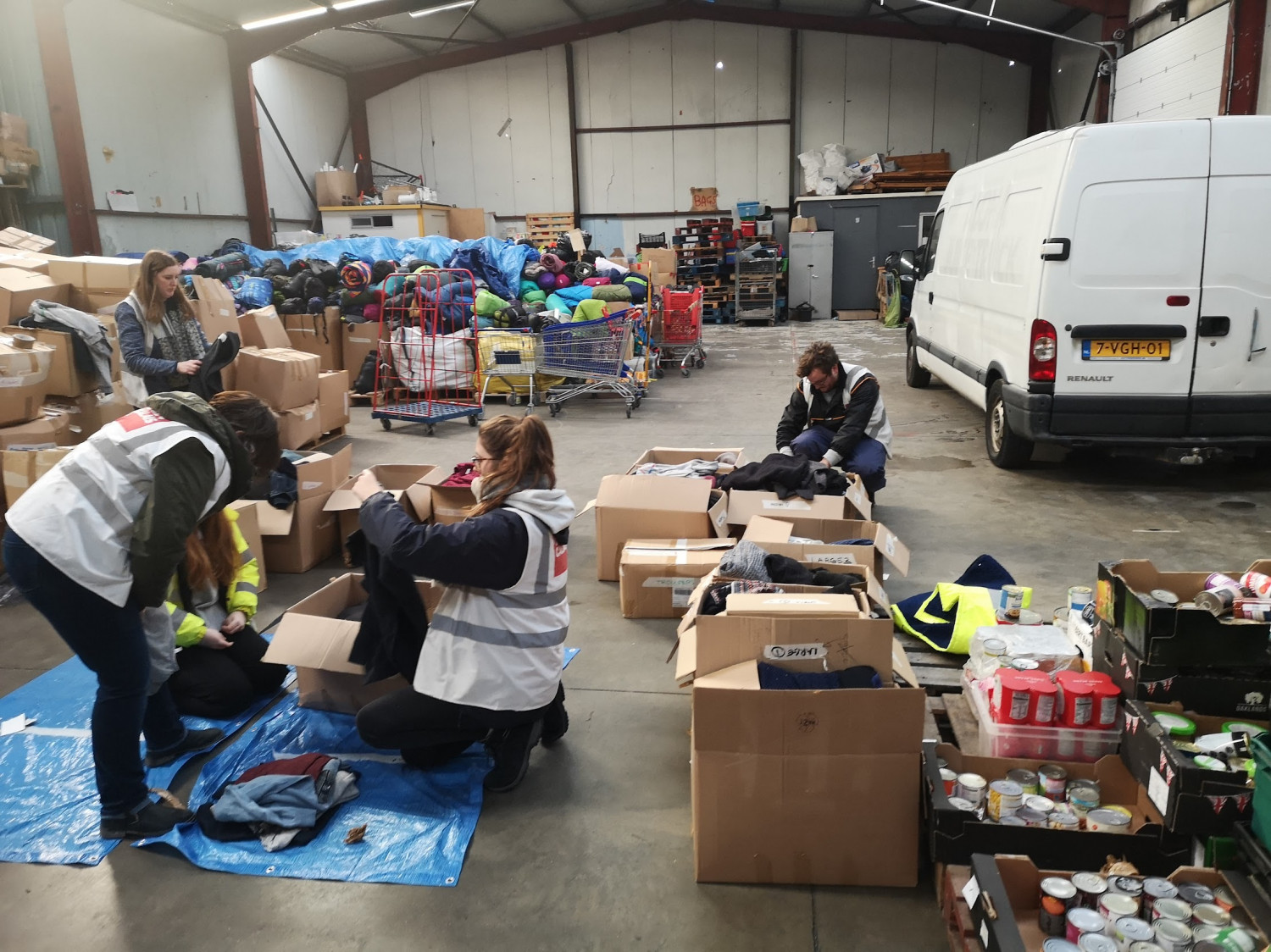 Workers in a warehouse sorting through clothing and foodstuffs for refugees