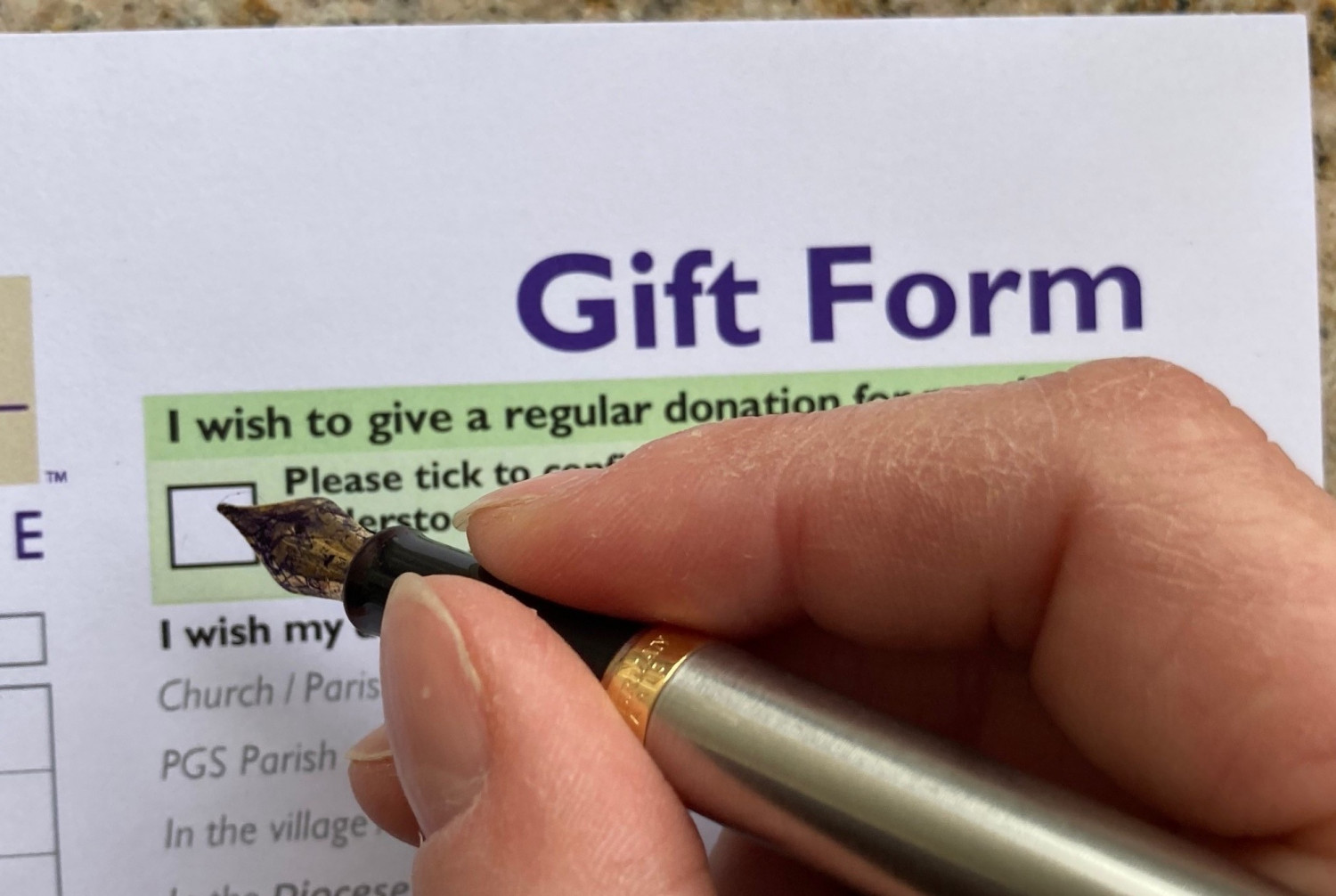 Someone ticking a box on a gift form to donate money