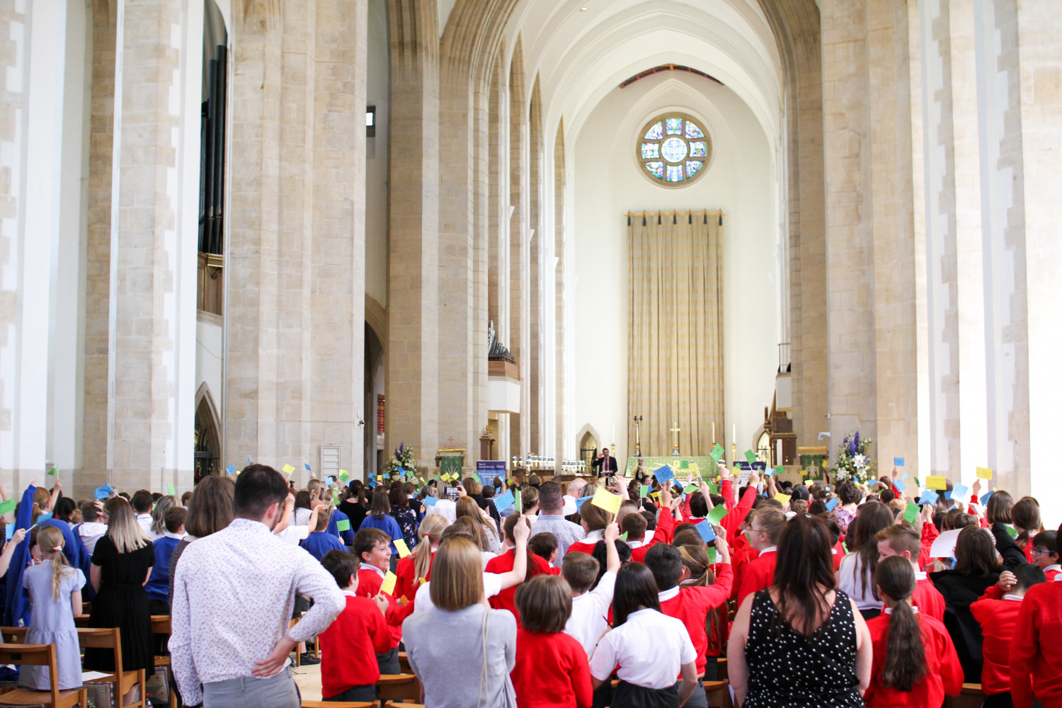 School children holding up flags and celebrating in Guildford Cathedral